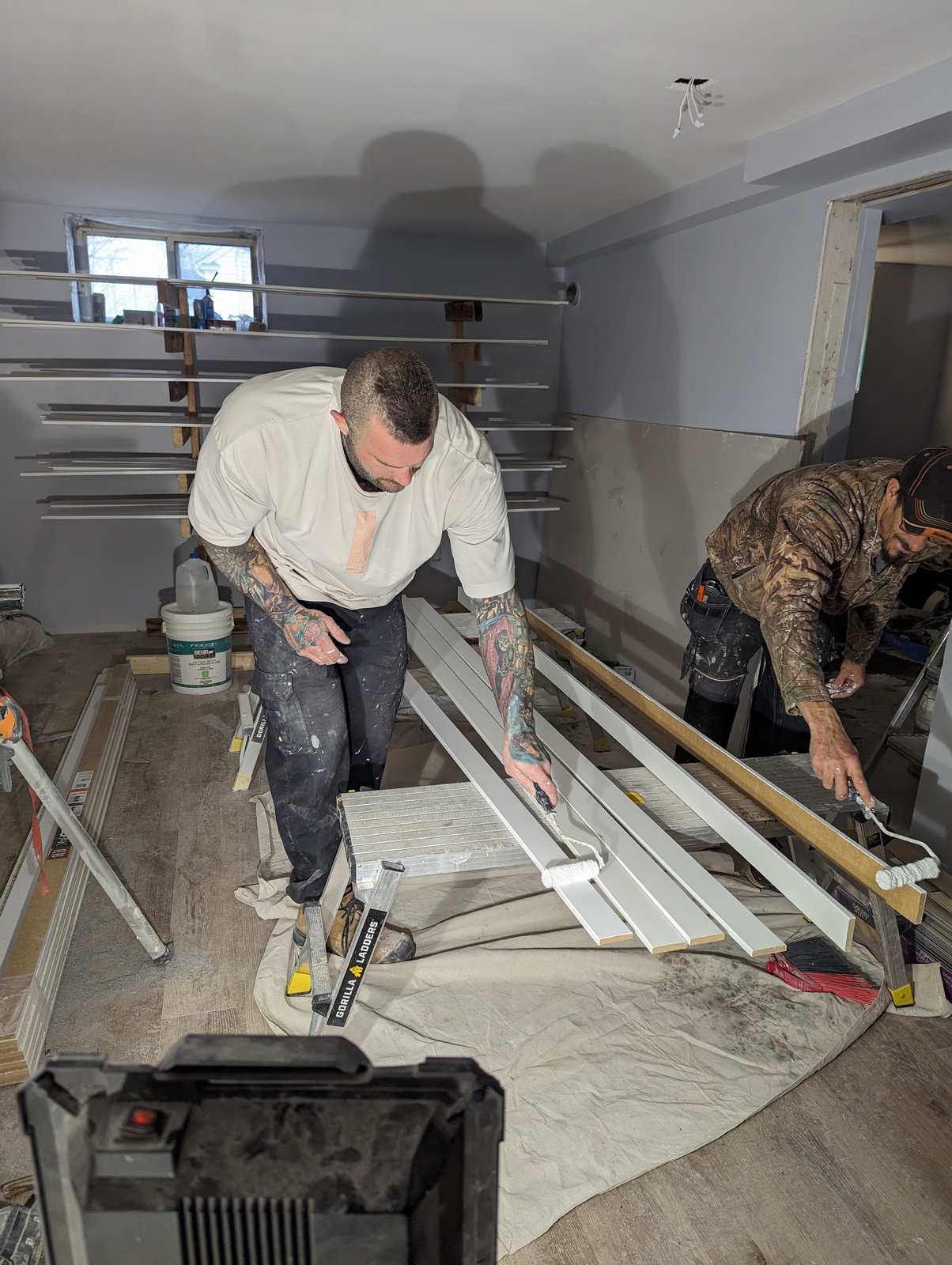 Valhalla Construction crew priming baseboard and trim on site during a basement renovation, Riverview NB