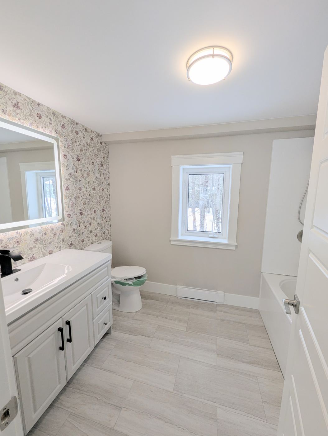 Completed bathroom remodel with vanity, wallpaper and plank flooring by Valhalla Construction