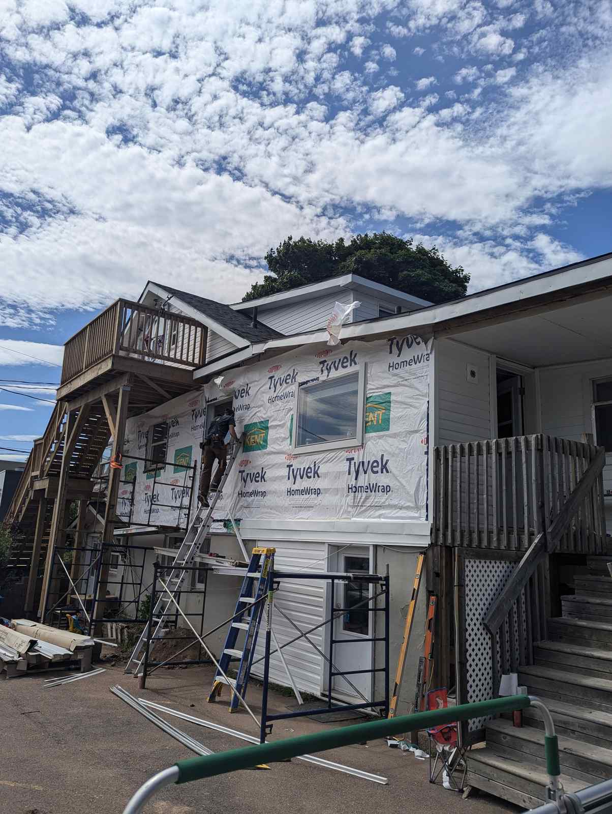 New vinyl siding progress on a home with a rear deck in Dieppe, NB
