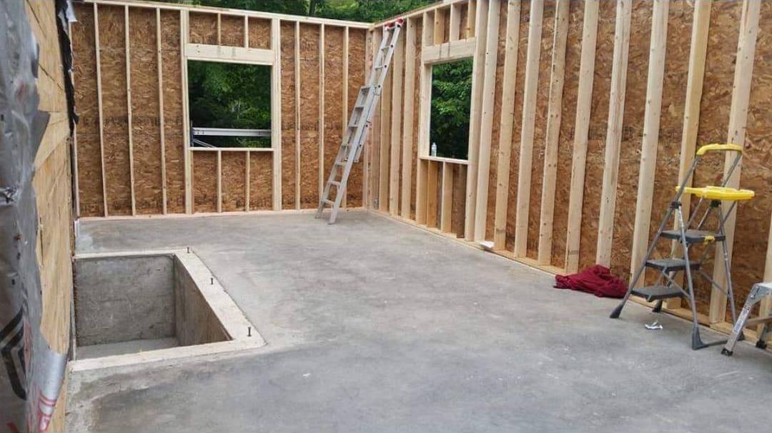 Interior of a home addition with framed walls, window openings and concrete slab