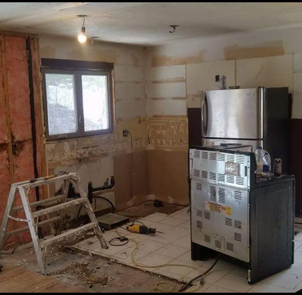 Kitchen stripped to bare walls and subfloor with plumbing stubbed out before renovation