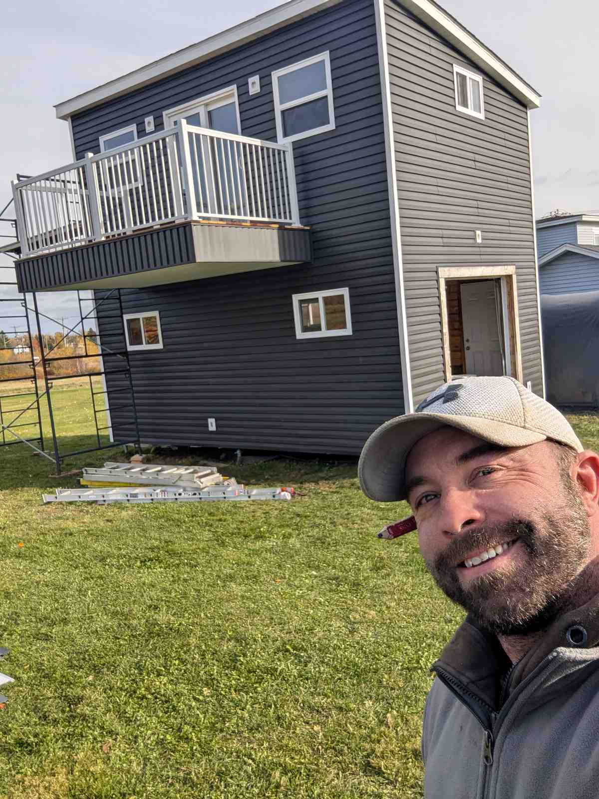 Finished two-story accessory building with dark panel siding and balcony, Notre Dame NB