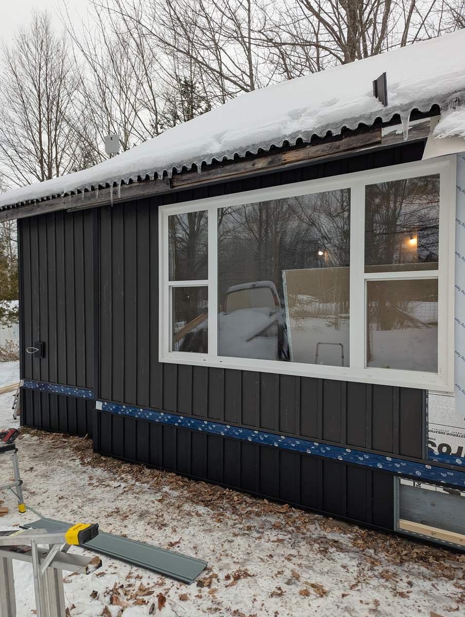 White window trim detailed into black vertical siding
